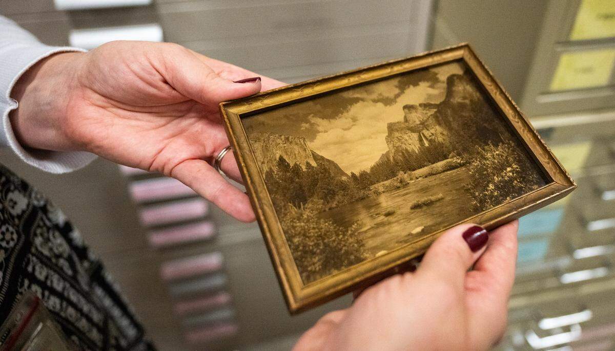 An orotone image of the Yosemite Valley, circa 1910, is held by the California State Library’s Jessica Knox-Jensen, in the library vault on Thursday. Orotones, positive photographic images on glass made from bronze powders mixed with gelatin or collodion emulsion, seem almost three dimensional when viewed. 