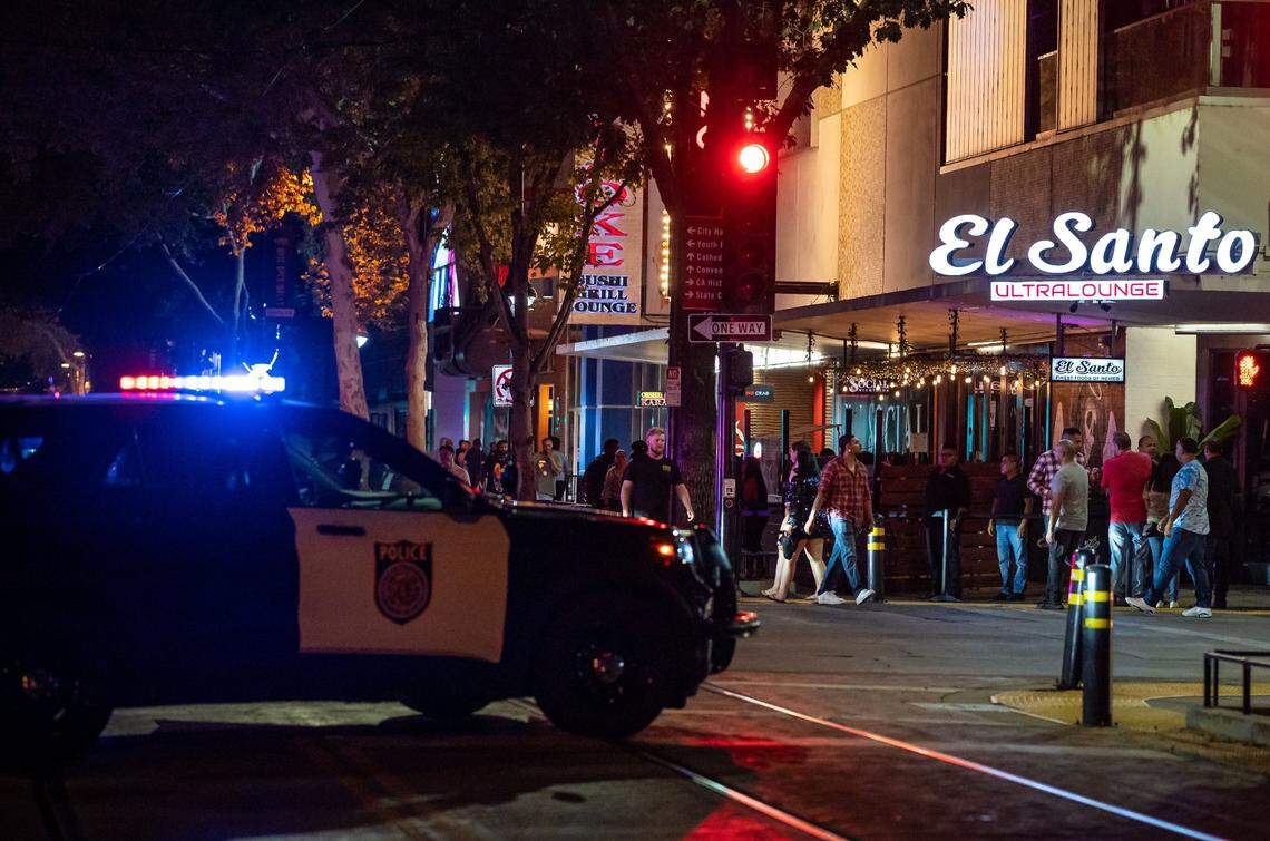 People walk around outside El Santo Ultra Lounge at the corner of K and 10th streets as bars and nightclubs prepare to close for the night in downtown Sacramento last month. Police park cars to close part of K Street as they keep a presence during that time, while patrons leave establishments to head out of the area or mingle nearby.