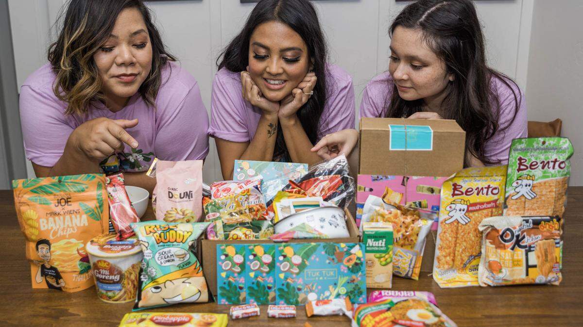 From left to right: Tuk Tuk Box co-founder Christy Innouvong, co-founder Beatriz Aurelio-Saguin and operations manager Allison Barcelon lay out the contents of one of their snack boxes.