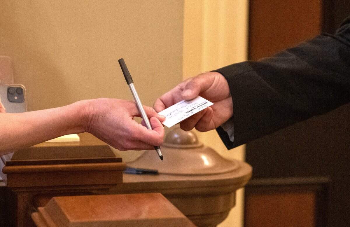 Lobbyist Natasha Minsker gives a card to Assistant Sergeant Tony Montalvo for Assemblywoman Eloise Gómez Reyes, D-Colton, on Tuesday. Some legislators put themselves on a list that indicates they do not accept lobbyist cards.