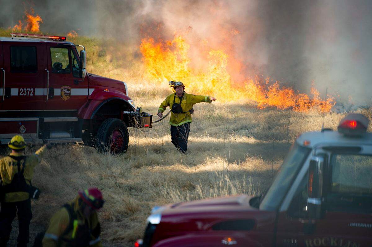 Members of the Roseville and Rocklin fire departments, along with Cal Fire, fight the Duluth Fire as it burns fields behind the Blue Oaks neighborhood of Roseville on Monday, Aug. 10, 2020.