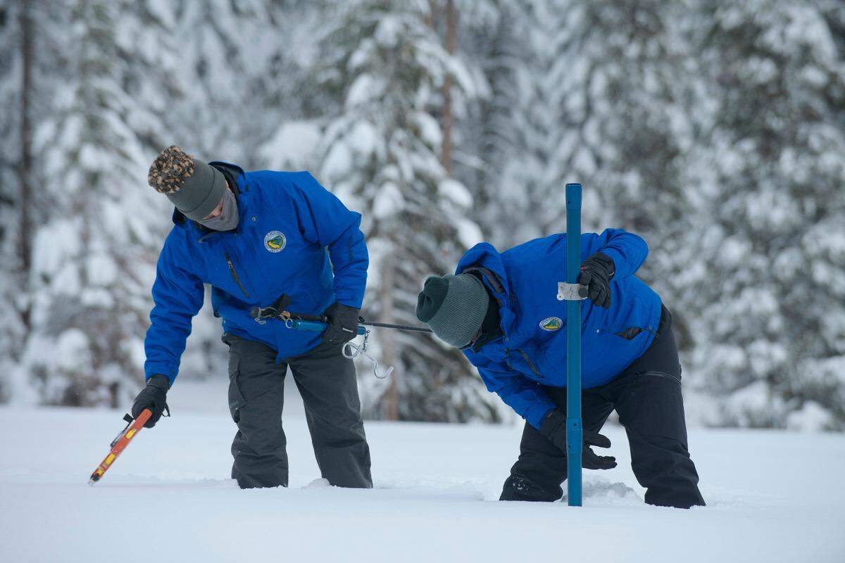 Anthony Burdock, left, and Sean de Guzman, chief of snow surveys for the California Department of Water Resources, check the depth of the snow pack during the first snow survey of the season at Phillips Station near Echo Summit on Thursday. The survey found the snowpack at 78.5 inches deep with a water content of 20 inches. Statewide, the snow holds 160% of the water it normally does this time of year.
