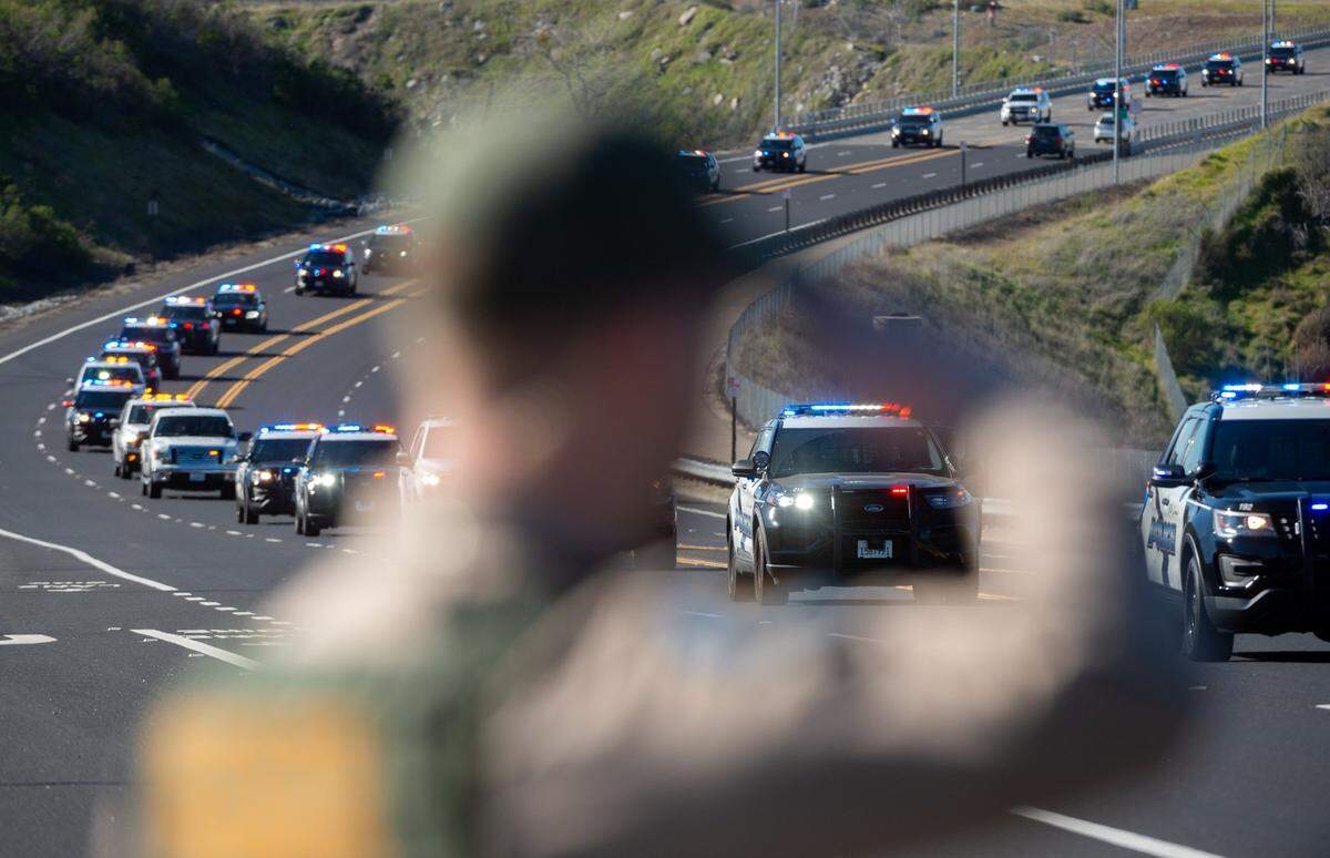 California State Park Ranger Jonathan Geneste salutes as the funeral procession for Elk Grove police officer Tyler Lenehan crosses the Folsom Lake Crossing bridge on its way to his final resting place in the community of Rescue on Tuesday, Feb. 1, 2022.