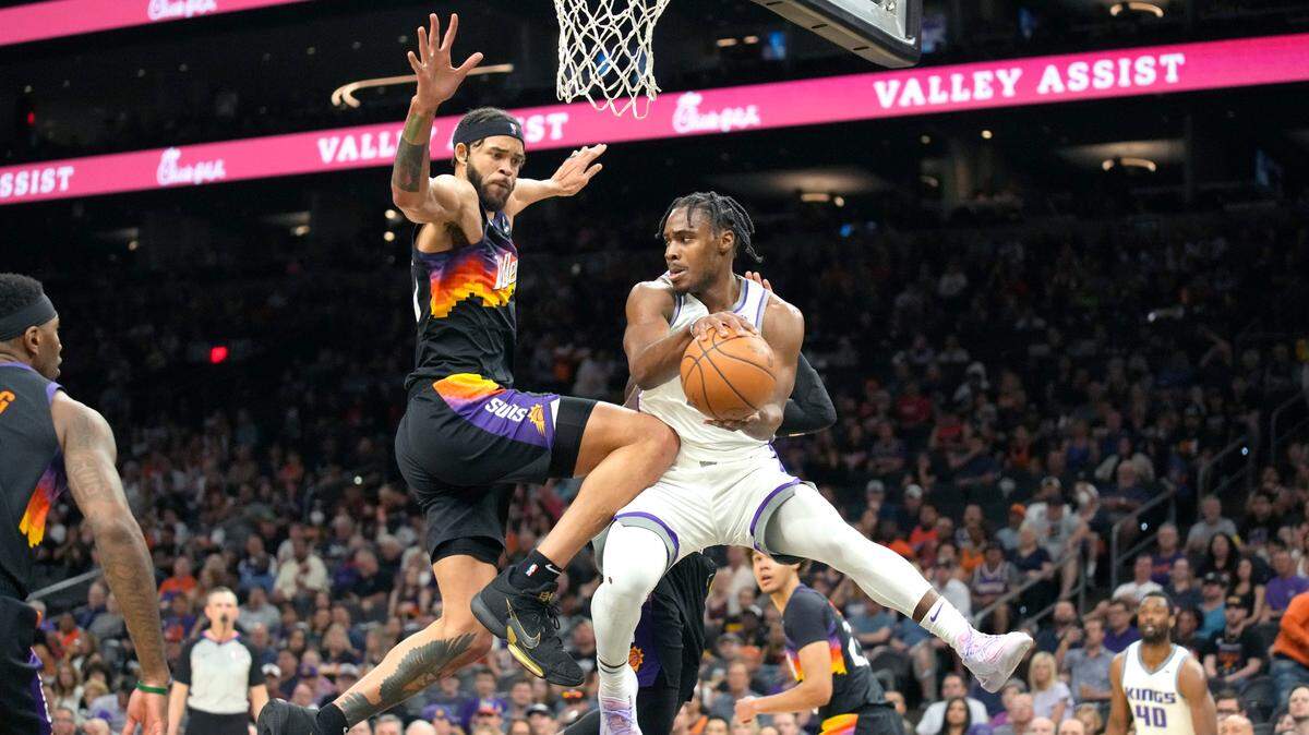 Sacramento Kings guard Davion Mitchell (15) drives on Phoenix Suns center JaVale McGee during the first half of an NBA basketball game, Sunday, April 10, 2022, in Phoenix. (AP Photo/Rick Scuteri)