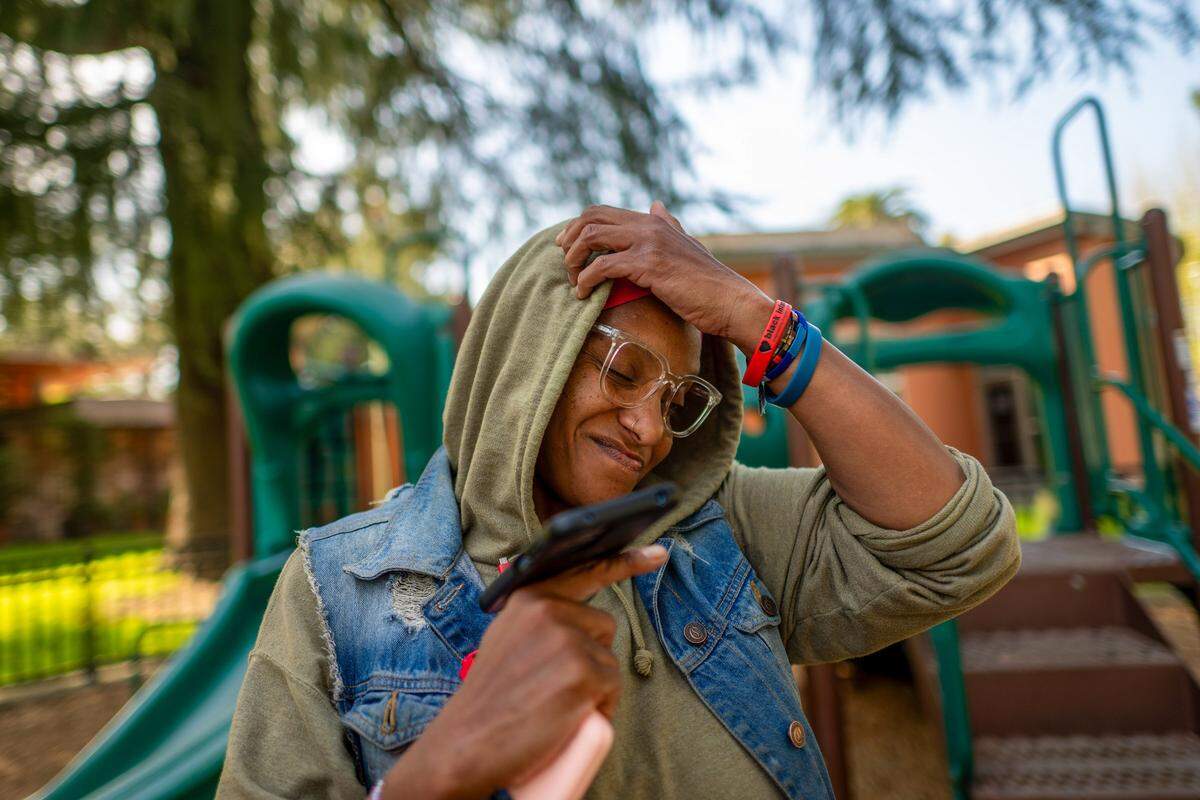 Tanika Williams, 40, shows signs of frustration as she calls the city’s 211 emergency shelter line for the second time as she stands in James Marshall Park in Sacramento on March 9. She, her husband and their daughter are homeless. A 211 operator said all shelters were full.