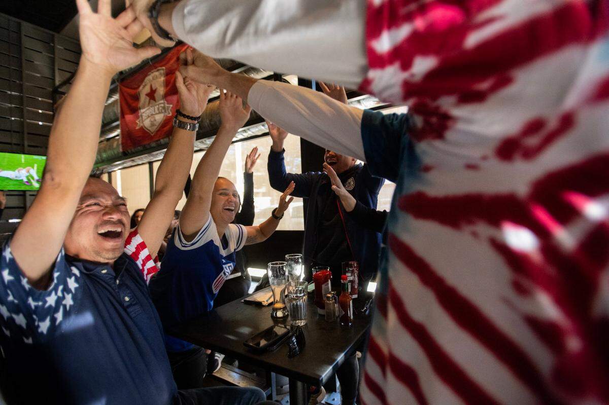 Jimmy Tran high-fives Jim Mankiewicz on Tuesday, Nov. 29, 2022, after Team USA beat Iran 1-0 in a must-win match to advance from group play in the World Cup tournament. Tran and Mankiewicz were enjoying the game with Alyssa Awarane and Michael Luu, in background, at a watch party at Public House on 16th Street in downtown Sacramento. 