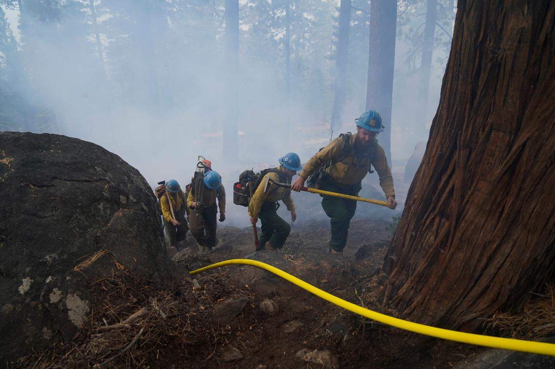 Members of a hotshot crew hike up the mountain while battling the Caldor Fire in South Lake Tahoe, Calif., Friday, Sept. 3, 2021. Fire crews took advantage of decreasing winds to battle a California wildfire near popular Lake Tahoe and were even able to allow some people back to their homes but dry weather and a weekend warming trend meant the battle was far from over.