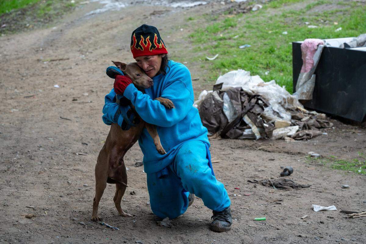 Victoria Reyes clutches one of her four dogs that got loose during a homeless encampment sweep near the Sacramento Northern Bike Trail in North Sacramento on Wednesday. She said no homeless shelter would accept her with the four dogs, and she did not want to give them up. “They have saved my life,” she said.