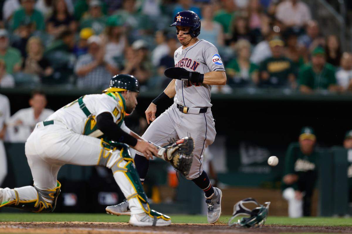 Jun 17, 2025; West Sacramento, California, USA; Houston Astros second baseman Mauricio Dubón (14) avoids the tag by Athletics catcher Austin Wynns (29) to score a run during the fifth inning at Sutter Health Park. Mandatory Credit: Sergio Estrada-Imagn Images