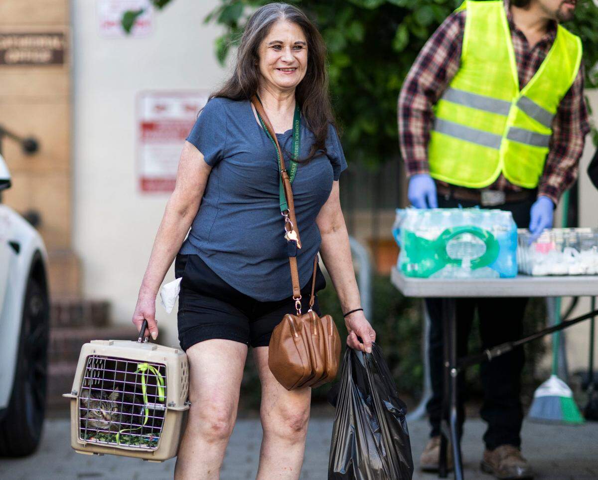 Annette Mechill, she carries her cat Sissy, takes a bag of food from the Brown Bag Lunch program at the Cathedral of the Blessed Sacrament on Thursday. The program hopes to partner with the city to distribute food.