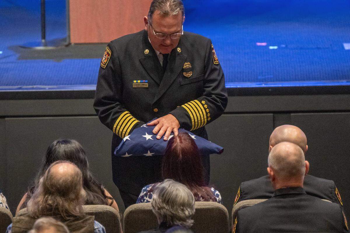 West Sacramento Fire Chief Steve Binns gives a flag to Susan Hall, wife of firefighter Tim Hall, at a memorial service for him at Creekside Christian Church in Elk Grove on Tuesday.