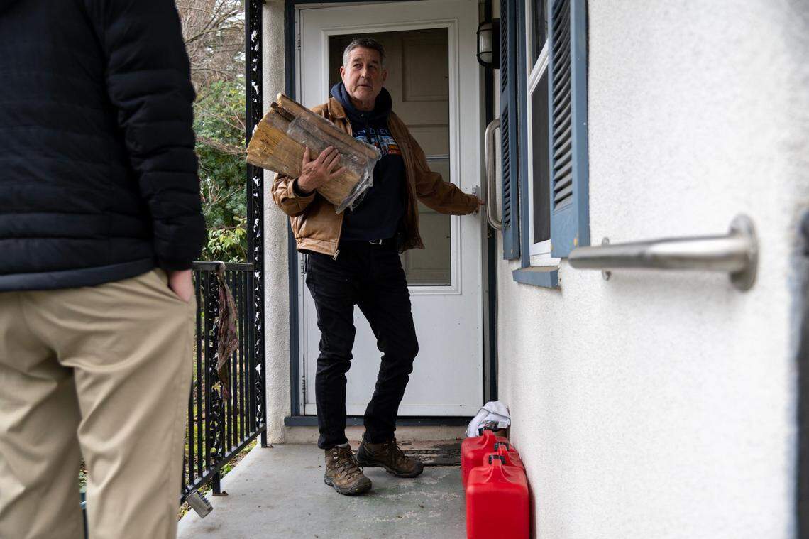 David Cropp talks with Josh Van Meter, the nephew of one of Linda Barnard’s caregivers, as he brings firewood to heat her home after she lost power in the storms last week in the Woodlake neighborhood of Sacramento on Tuesday.