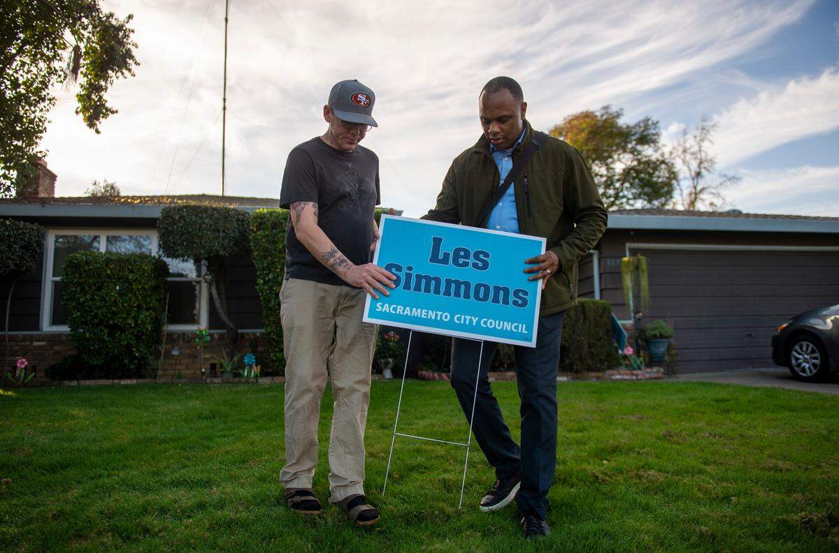 Pastor Les Simmons, right, is helped by Meadowview resident Richard Santa Cruz as he puts up a lawn sign in his front yard, Saturday, Feb. 2, 2020, while out campaigning for Sacramento City Council District 8 race for the upcoming March election.