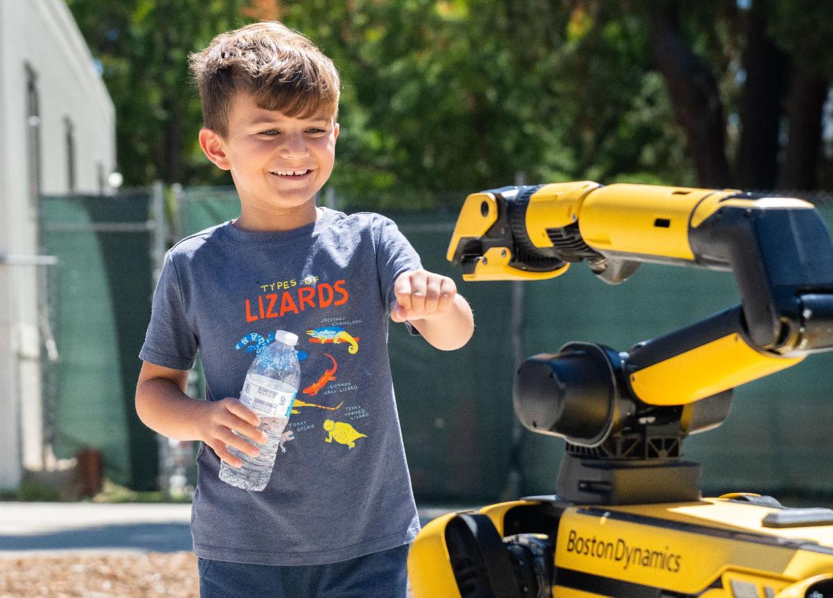 Jacob Jaquith, 5, reaches out to give Boston Dynamics’ robot dog Spot a fist bump outside the state Capitol on Thursday. “This thing is really cool,” said Steve Jaquith, Jacob’s dad.