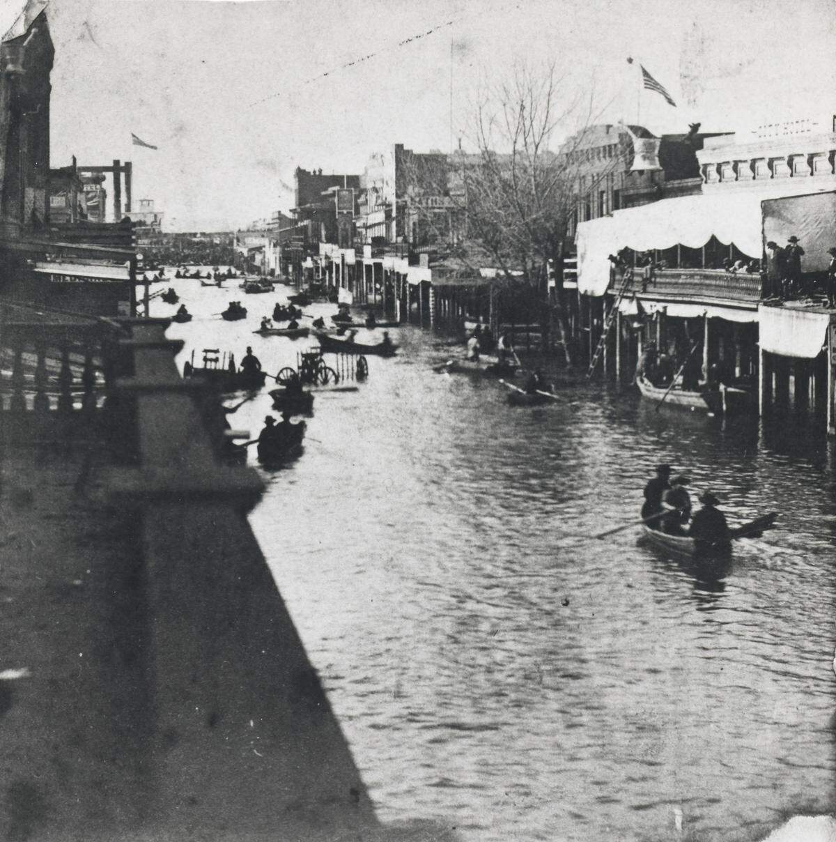 Boaters navigate Sacramento's K Street after the precipitation of December 1861 and January 1862.