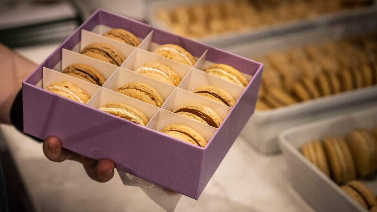 An employee at Ginger Elizabeth holds a box of macarons in 2022.