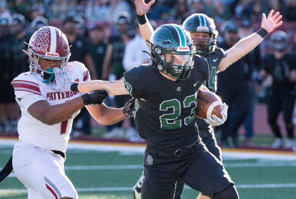 Twelve Bridges Raging Rhinos running back Braeden Ward (23) stiff arms a Patterson Tigers defender on his way to a 30-yard touchdown run in the first quarter of the Sac-Joaquin Section Division IV championship game in November. Ward is The Bee’s Small School Player of the Year.