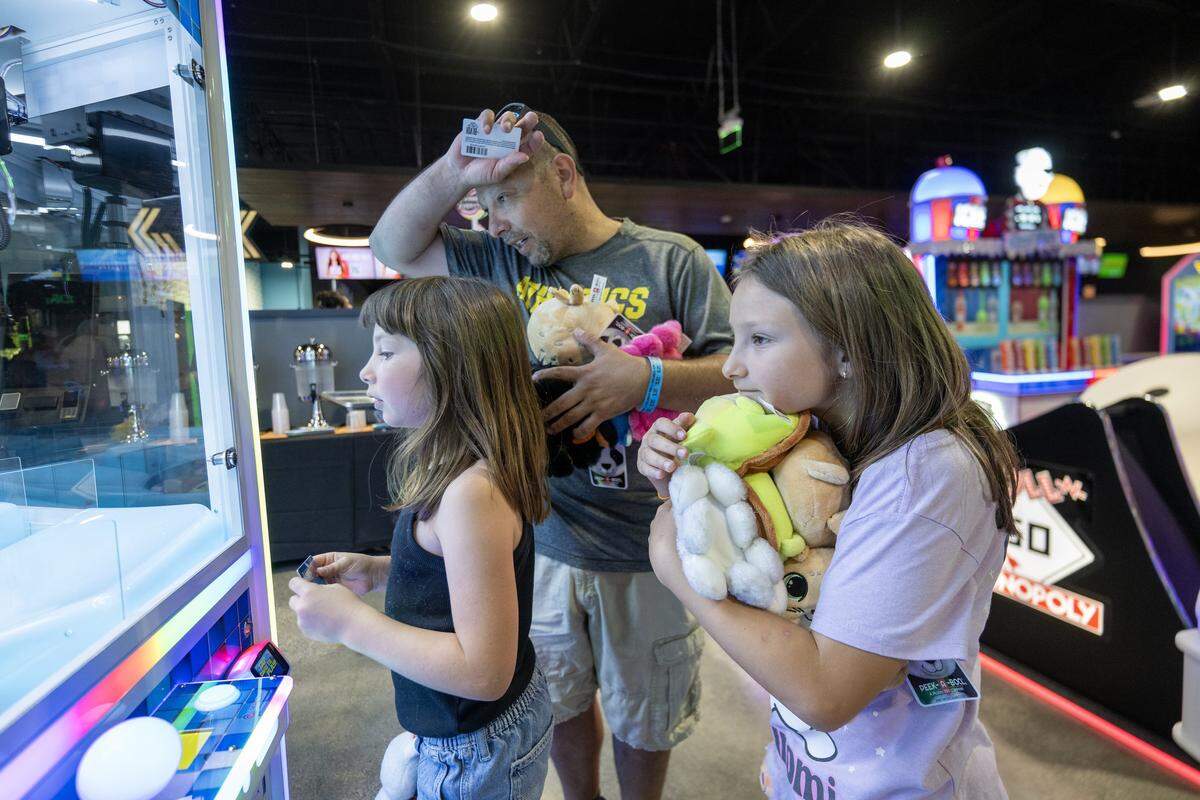 Herman Mendoza collects stuffed animals with his kids Aria and Della at the BLVD in West Sacramento on Wednesday.