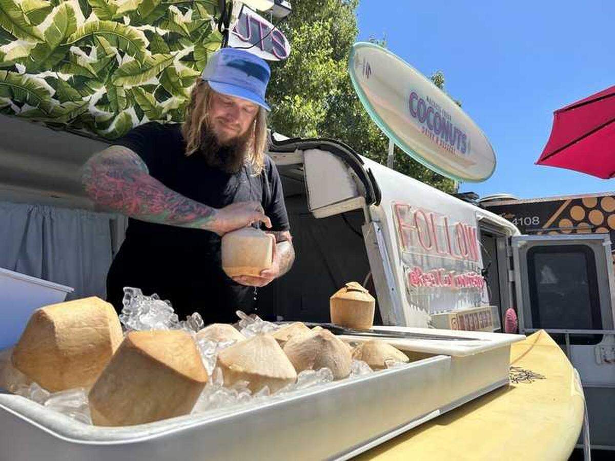 Dustin Ryen, also known as the Coconut Guy, breaks open a raw coconut served fresh on ice at his Machete Fresh Coconuts stand at the California State Fair on Friday.
