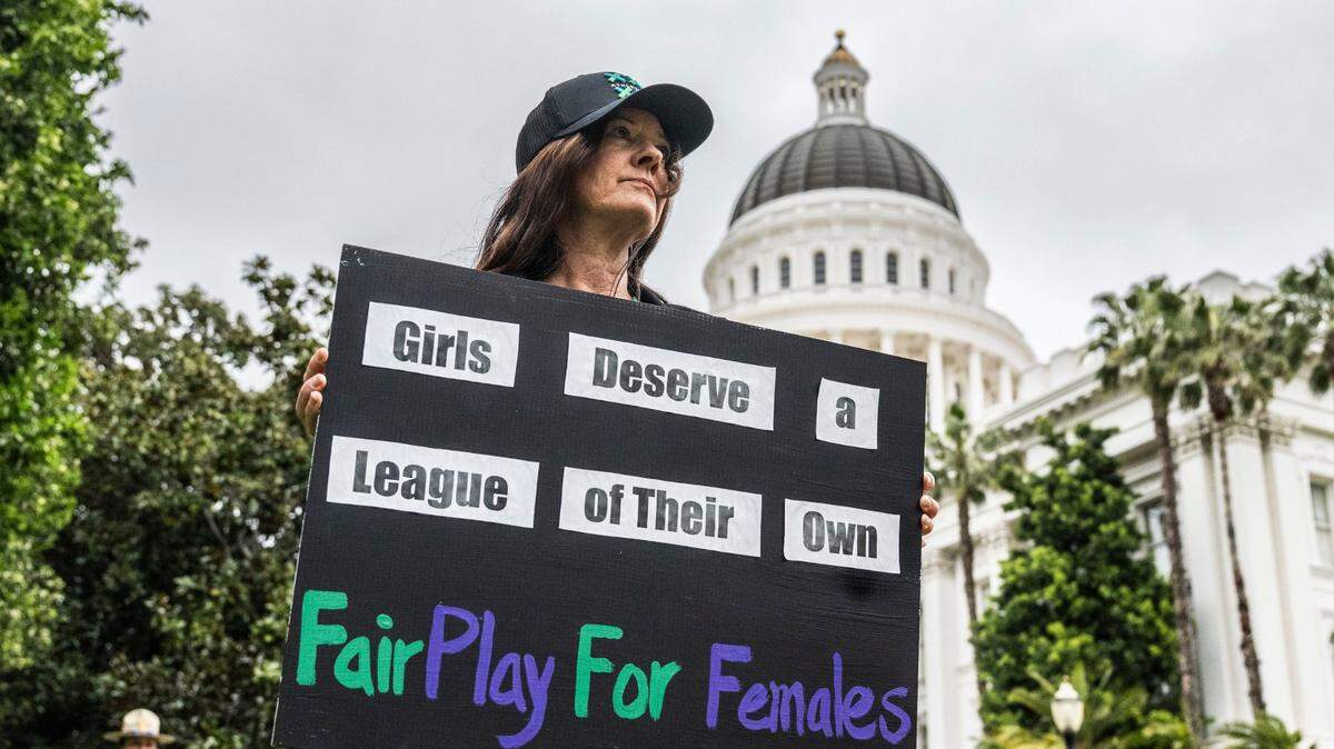 Lisa Smith, of Santa Cruz, holds a sign on Tuesday, April 1, 2025, during a rally at the state Capitol for two bills that would block transgender student athletes from participating in sports. An Assembly committe heard public comment on the bills later in the day.