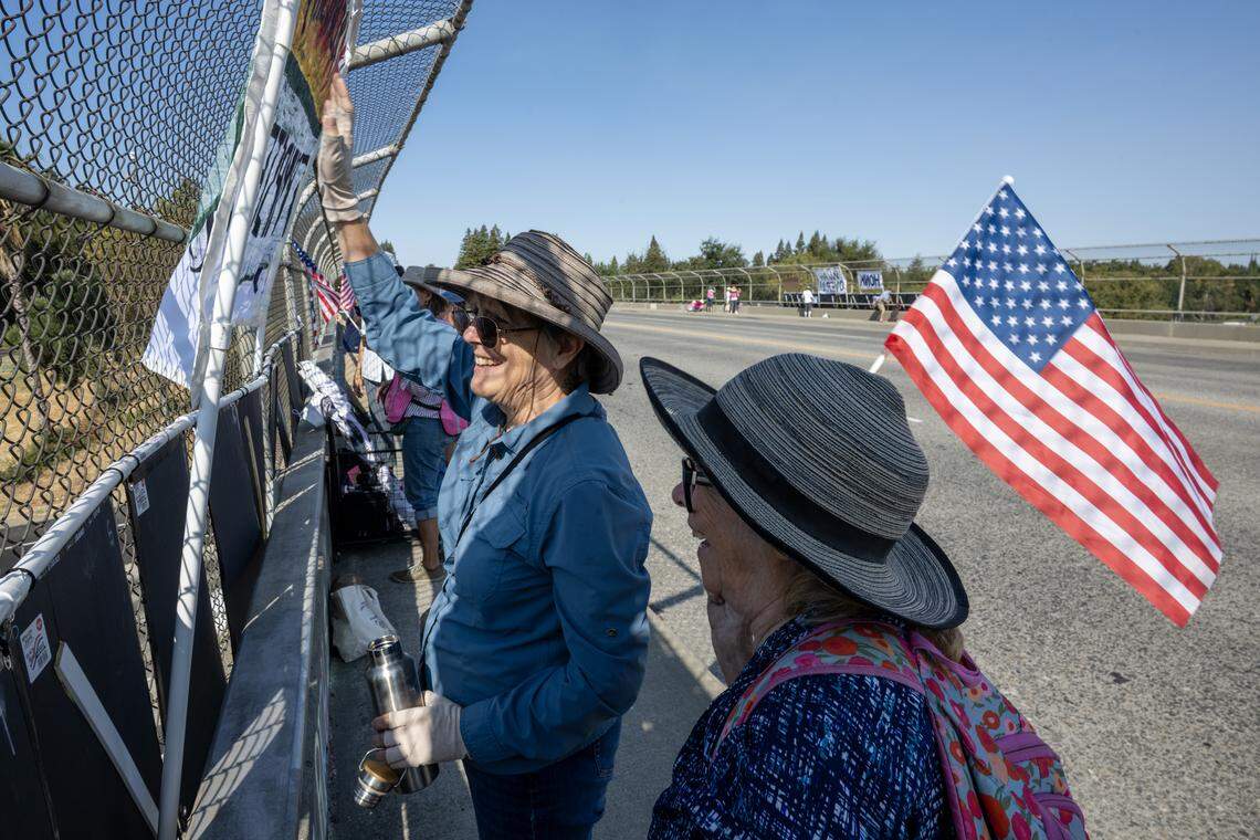 Ann Russell, center, waves to oncoming traffic from the overpass on Interstate 5 on Pocket Road in Sacramento during a protest against President Trump and his administration on Saturday.