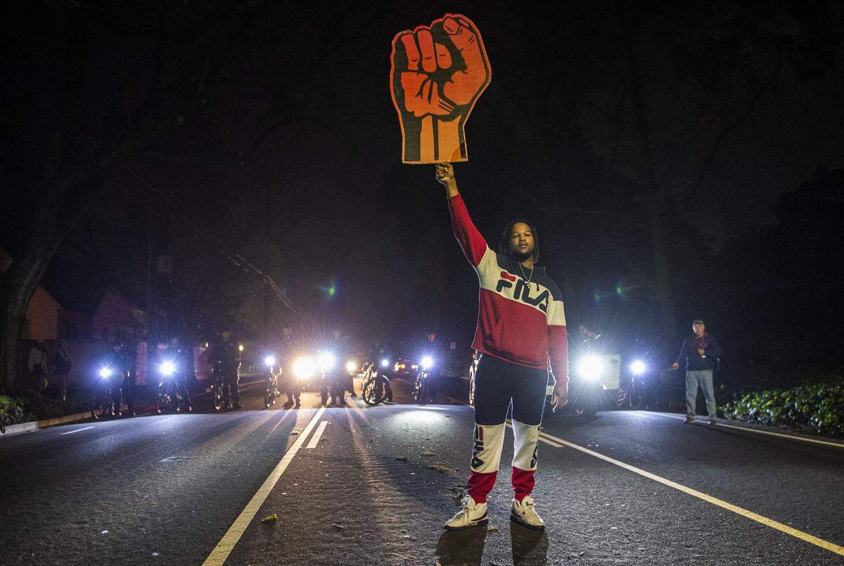 A protester holds up a sign shaped like a large fist as a line of Sacramento police officers block Folsom Boulevard in East Sacramento on Monday. The march, in protest of the Sacramento County DA’s decision not to charge the officers who shot and killed Stephon Clark, ended with more than 80 people arrested.