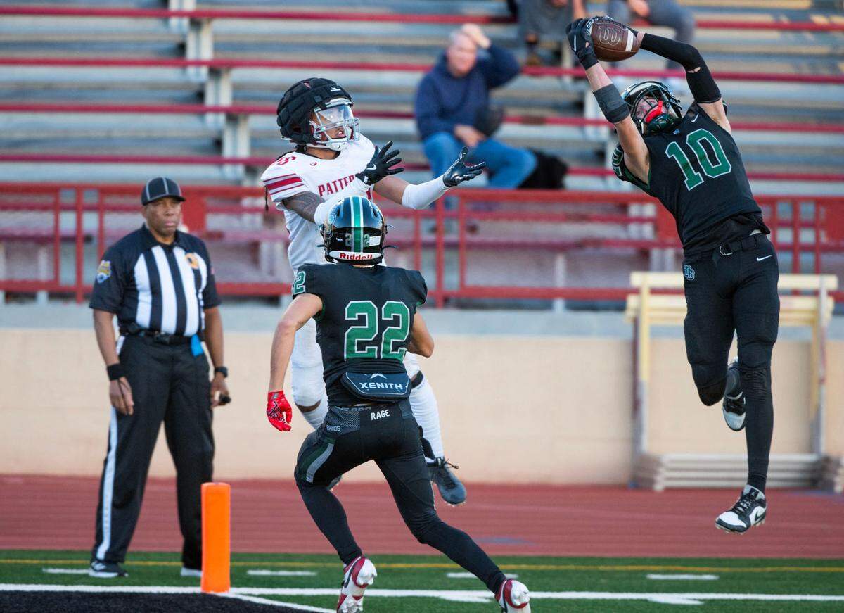 The Twelve Bridges Raging Rhinos’ Dylan Amos (10) leaps in front of Patterson Tigers’ Romeo Manu (26) for an interception near the end zone in the second quarter during the Sac-Joaquin Section Division IV championship game at Hughes Stadium in Sacramento on Friday, Nov. 29, 2024. 