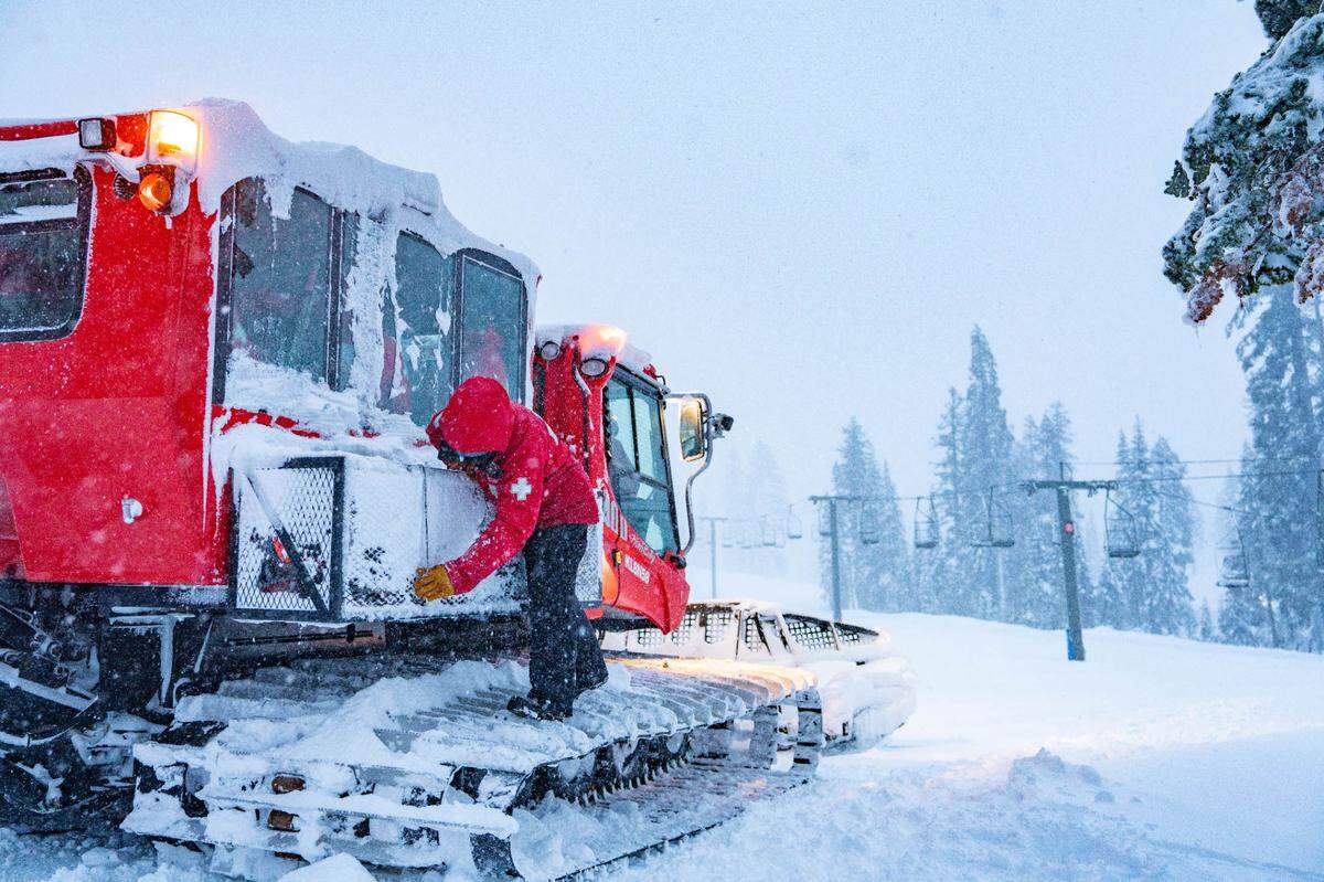 A ski patroller at Palisades Tahoe Ski Resort stands on a snow plow pushing new snowfall at the resort on Friday, Feb. 14, 2025.