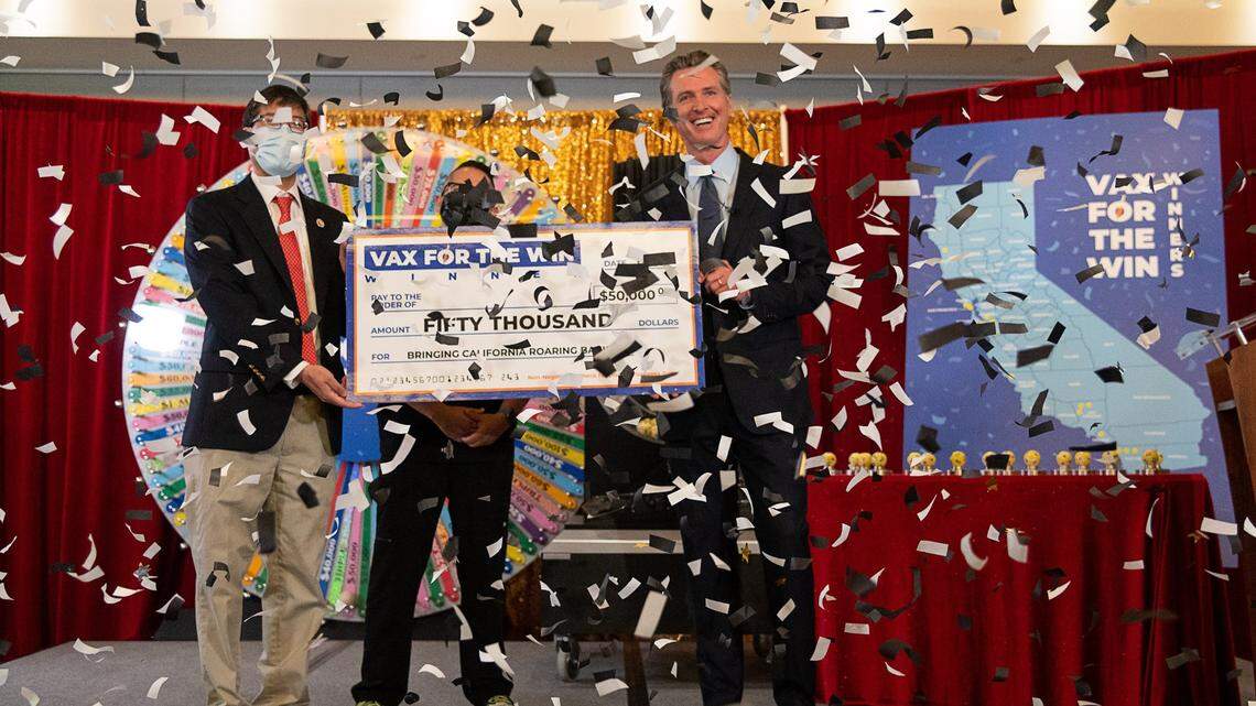 Governor Gavin Newsom, Senator Richard Pan and UC Davis Assistant Nurse Manager Claudio Alvarado hold a mock-up check for the first 15 Californians to be awarded $50,000 for getting vaccinated against COVID-19, at the California Lottery Headquarters on Friday, June 4, 2021, in Sacramento.