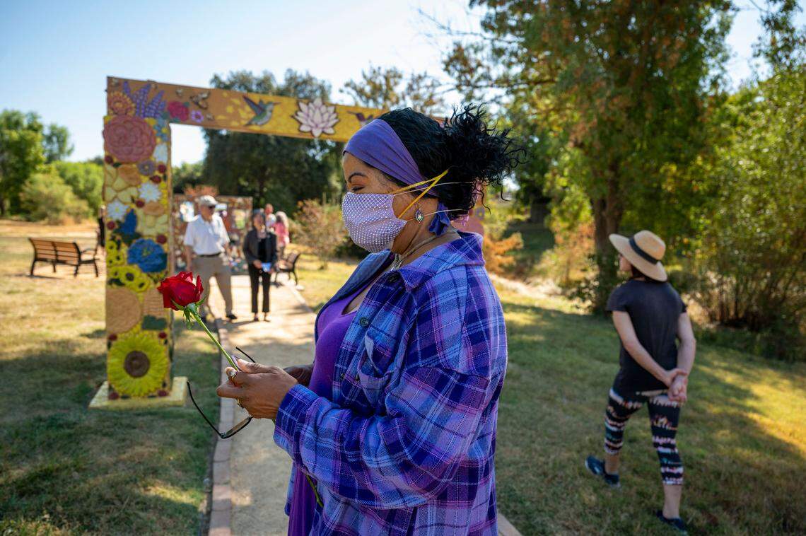 Sandy Holman of Davis holds a red rose given out during the COVID-19 Memorial dedication ceremony at the Davis Cemetery District on Sunday.