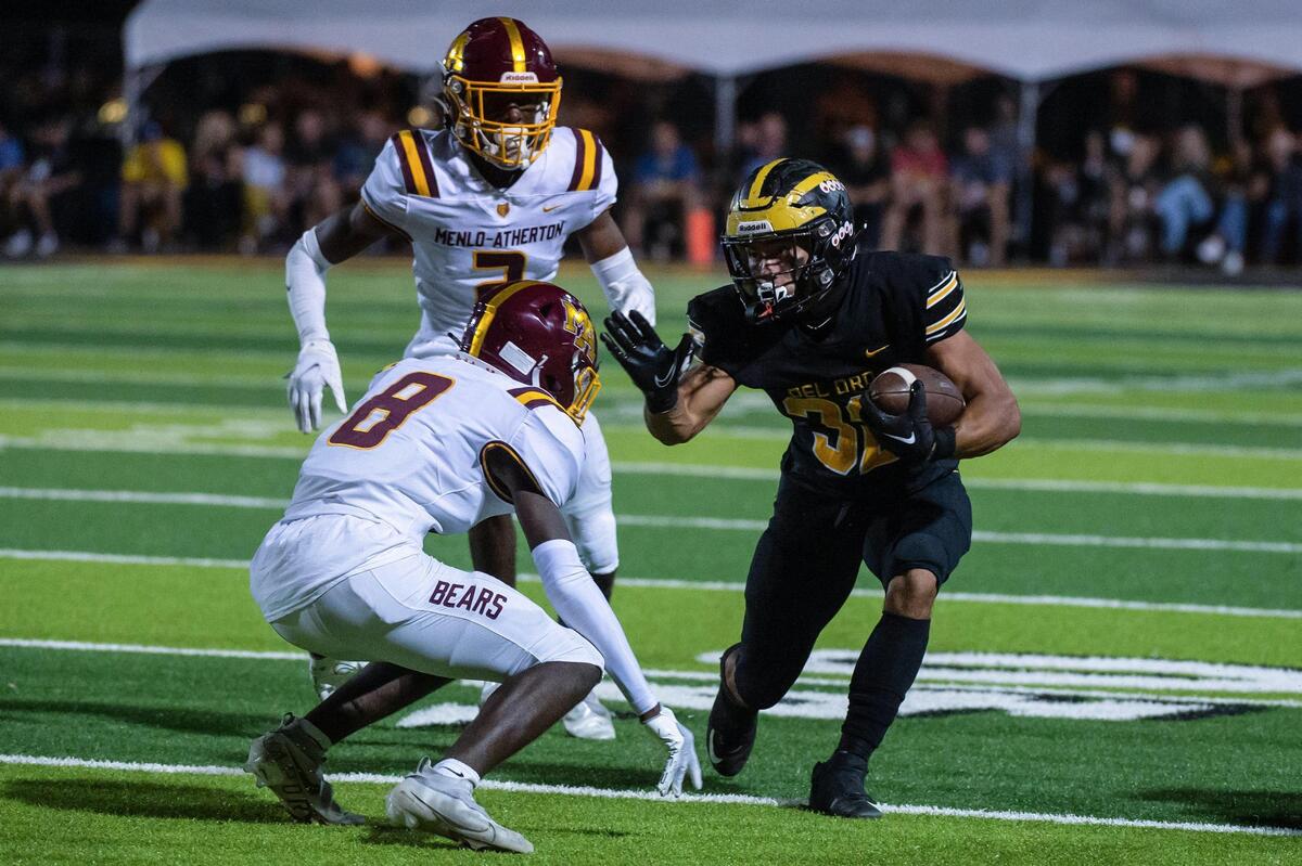 Del Oro’s Kainoa Acia (32) runs past Menlo-Atherton’s Sherrod Smith (8) during the second quarter in the game Friday at Del Oro High School in Loomis.