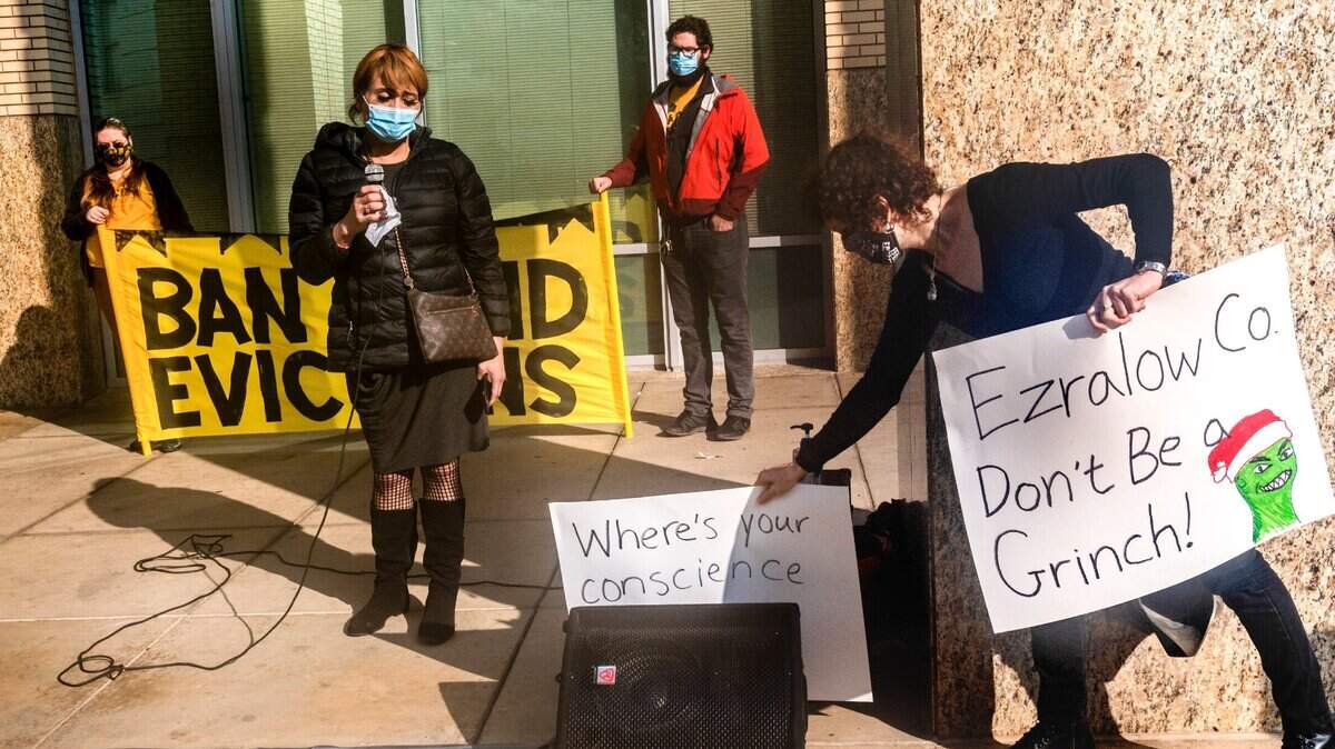 Sofia Garcia, a tenant at the Hawthorn Suites on the verge of eviction, speaks during a press conference as Delphine Brody, right, with the Sacramento Eviction Defense Network, places signs in protest against landlord Ezralow Company LLC in front of Sacramento City Hall on Monday, Dec. 21, 2020.