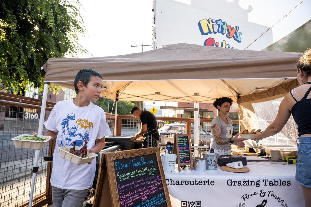 Buster Lee, 10, whose father Christopher Lee owns Flora & Fauna Provisions with partner Angelika Feldman, runs an order to a table at the pop-up eatery set up for the evening outside Nitty’s Cider in Sacramento in July. “They told us that it was really refreshing to have something so different at these food pop-ups,” Feldman said about a business where they had recently set up outside. “They were just very, very inspired to have something more light and airy and easier to eat that wasn’t so filling and fatty.”