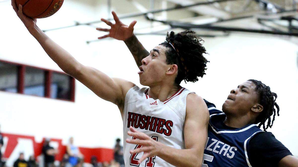 Centennial guard Jared McCain (24) flies to the hoop for a layup as Sierra Canyon guard Mike Price (5) defends in the second half of the CIF State Open Division boys basketball regional championship game in Corona on Tuesday.
