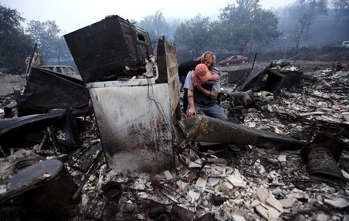 Sherri Marchetti-Perreault and James Benton embrace as they sift through the remains of their home in Klamath River along Highway 96 after it was destroyed by the McKinney Fire on Monday.