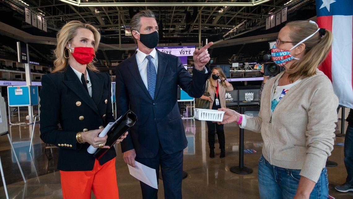 California Gov. Gavin Newsom, center, and First Partner Jennifer Siebel Newsom, left, drop off their tickets to Diane Hobler, right, after voting during COVID-19 protocols at Golden 1 Center in Sacramento on Thursday, Oct. 29, 2020.