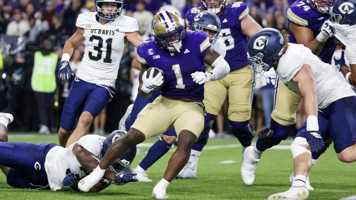 Washington Huskies running back Jonah Coleman breaks a tackle attempt by UC Davis Aggies defensive lineman Derrell Porter (35) to rush for a touchdown during the second quarter Saturday at Husky Stadium in Seattle. Coleman is a Stockton native.