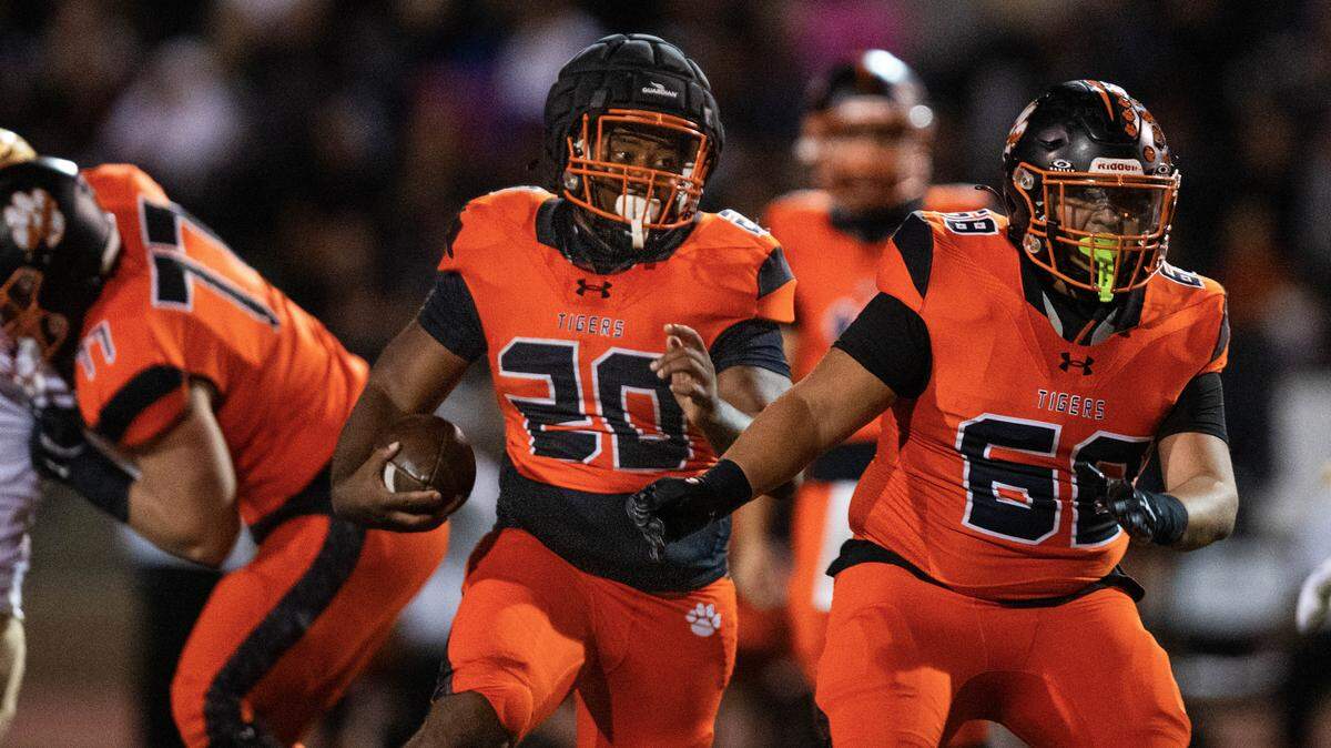 The Roseville Tigers’ D'marcis Gresham (20) rushes behind the blocking of of Danny Rubio (68) against the Nevada Union Miners on Friday in Roseville.