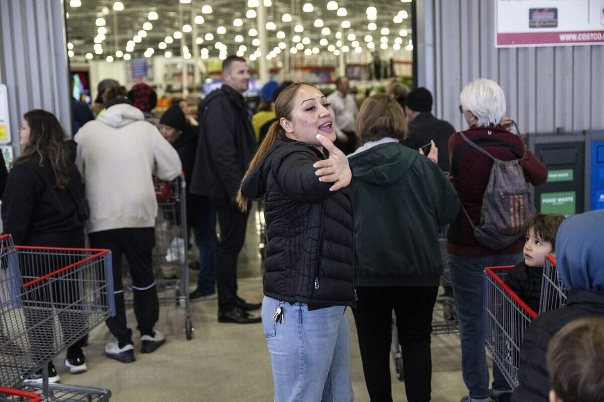 Lorena Martinez, a front-end supervisor at Costco, directs customers during a grand opening of their new store on Baseline Road in Roseville on Friday. The large demand for specialty liquor required two lines – one for liquor and one for all other products.