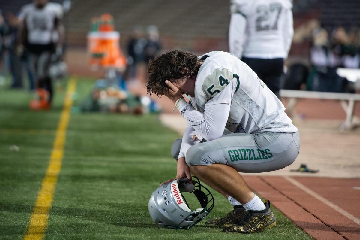 Granite Bay senior defensive tackle Talae Tuimaunei (54) holds his head in dejection after the CIF Sac-Joaquin Section Division II championship game Saturday, Nov. 26, 2022, at Hughes Stadium at Sacramento City College. The Buffaloes won 51-48.