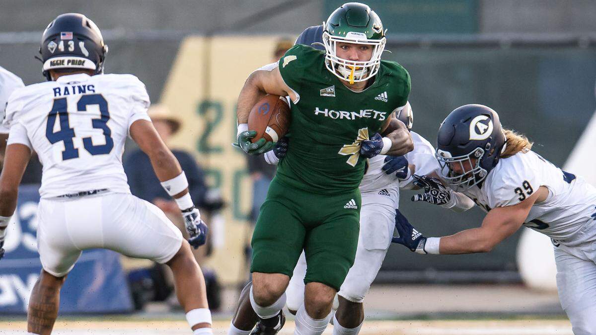 Sacramento State Hornets running back Cameron Skattebo (4) rushes for extra yards as UC Davis Aggies grasp at him during the Causeway Classic on Saturday. Skattebo was the Big Sky Offensive Player of the Year.