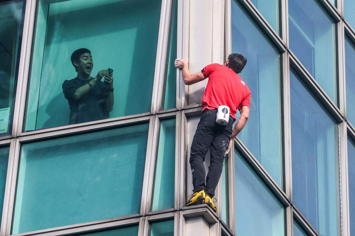 TOPSHOT - A building occupant uses his phone to record US rock climber Alex Honnold climbing the Taipei 101 building without ropes or safety gear in Taipei on January 25, 2026. (Photo by I-Hwa Cheng / AFP via Getty Images)