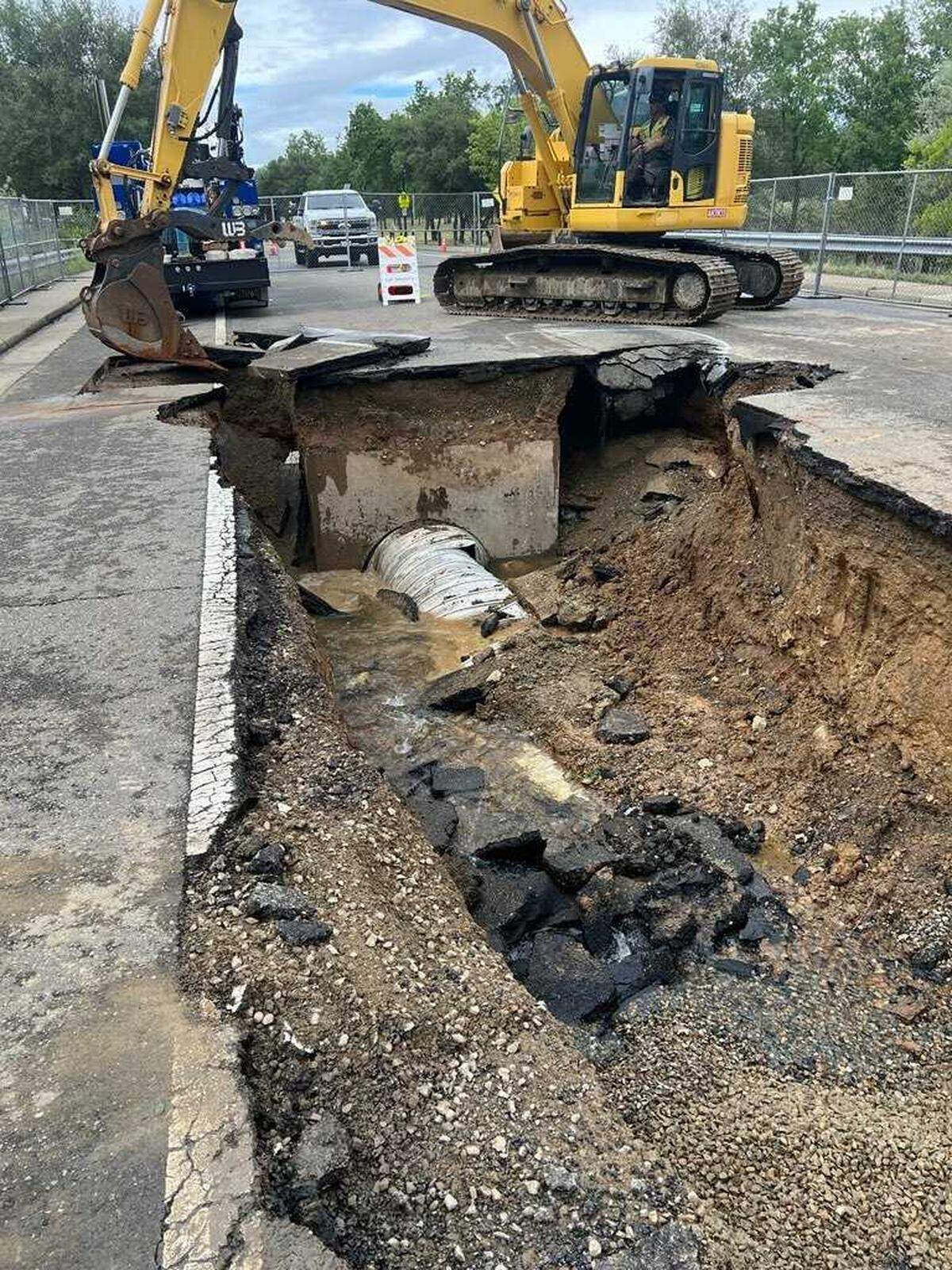 A large sinkhole blocks the intersection of Prewett and Newington drives in the Lexington Hills neighborhood of Folsom on Monday, April 13, 2026. The sinkhole opened after a series of weekend storms brought heavy rain to Northern California, prompting crews to install barriers and set up detours for residents.