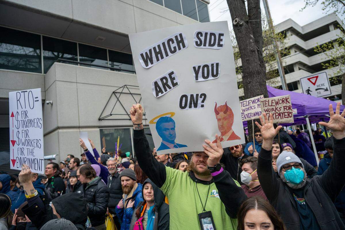 California Department of Food and Agriculture employee Andrew Boren, center, holds a sign as hundreds of state workers rally Wednesday at the offices of CalHR in Sacramento to protest Gov. Gavin Newsom’s order directing them to return to their offices four days a week.