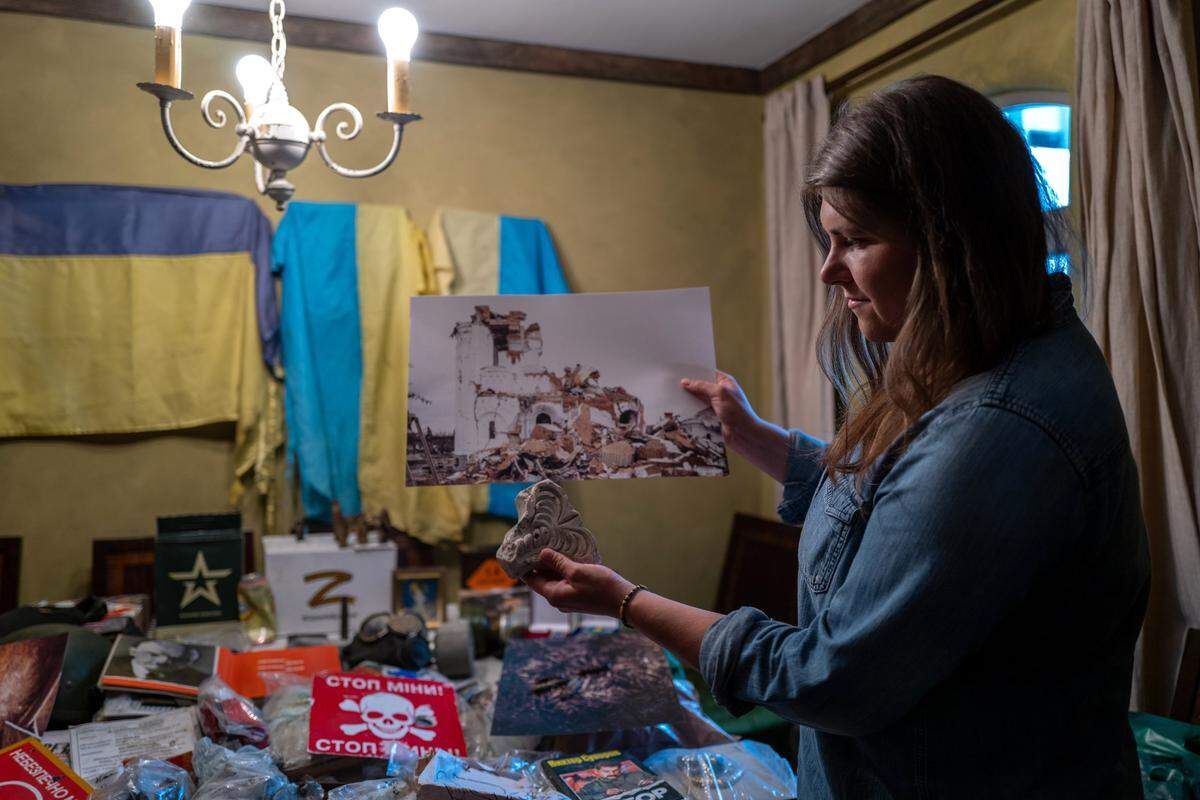 Alina Tyulyu holds a picture on Tuesday of a bombed Ukrainian church along with a piece of the building she collected when she was in the country helping refugees escape the war.