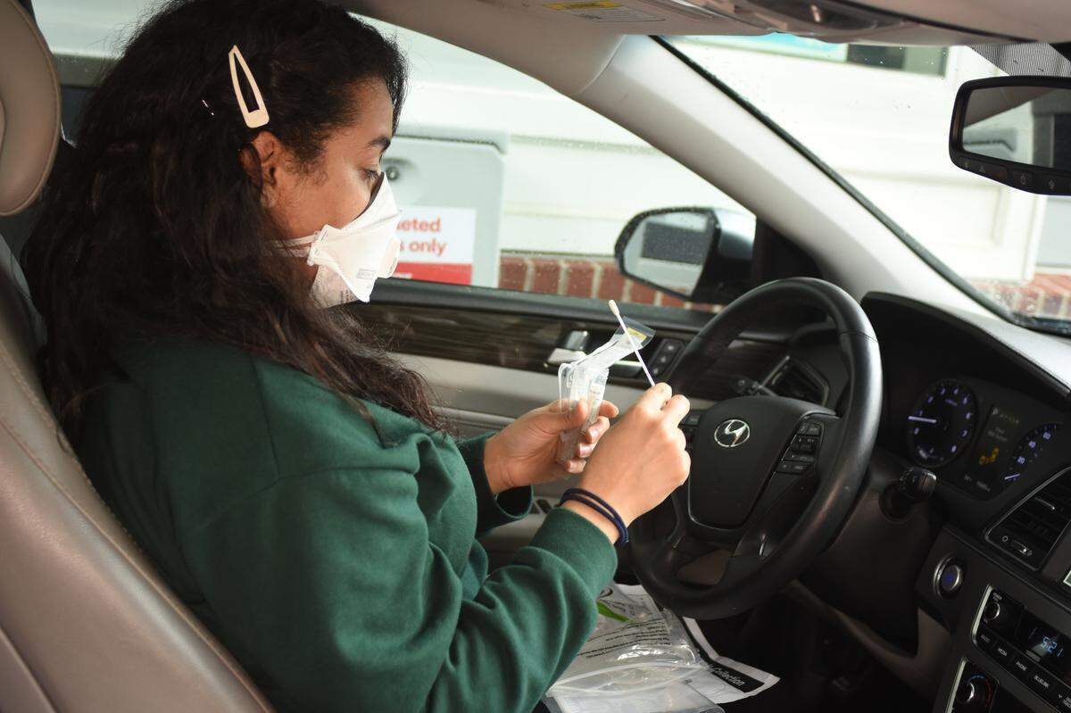 A patient prepares to administer a self-swab test for COVID-19 at a CVS drive-thru site.