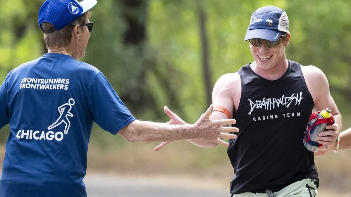 Sacramento FrontRunners founder James Evans-Brown high-fives Ryan Cate as he runs along the American River Parkway in Sacramento on Saturday.