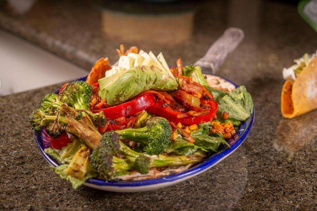 A fajita salad at Bambi Vegan Tacos in Sacramento is made with charred broccoli, burnt romaine, avocado, peppers, onion, achiote squash and roasted corn. It is served over a flour tortilla with refried pinto beans and avocado chili vinaigrette.