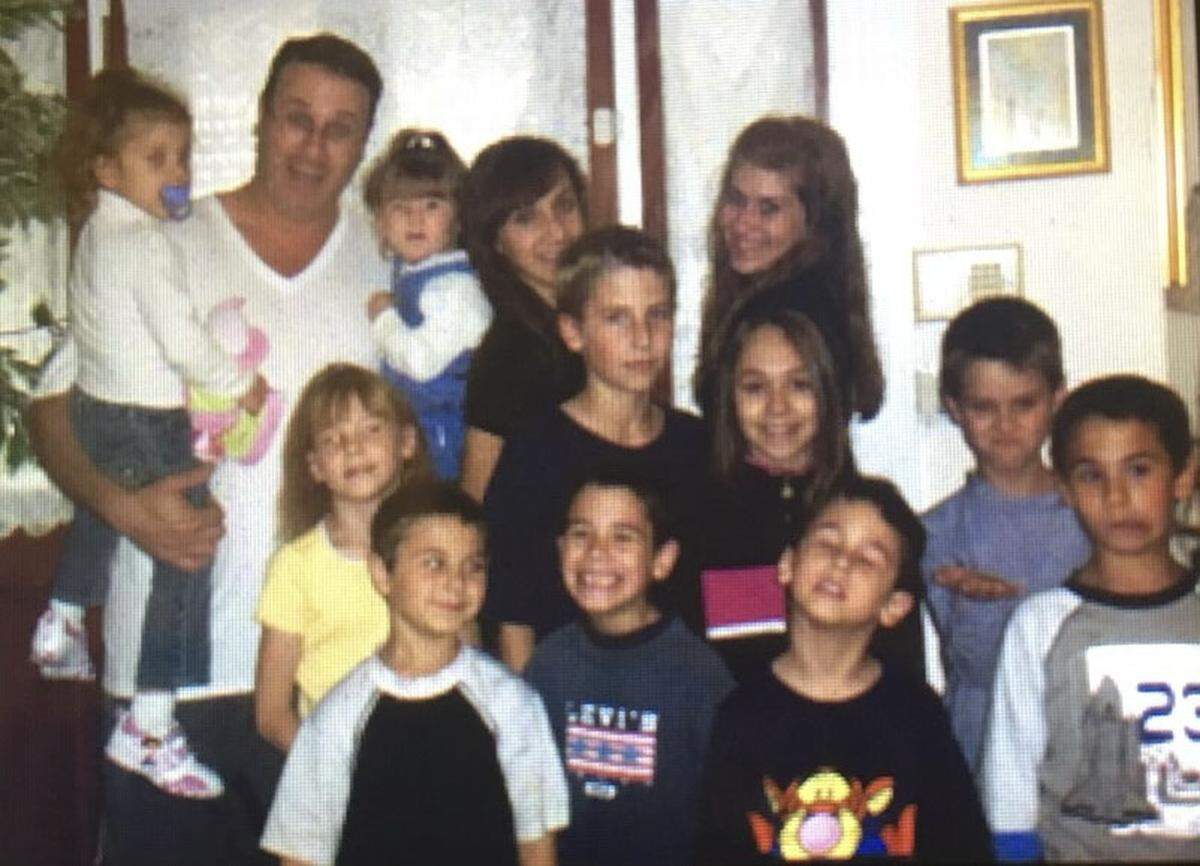 Norman Masters poses for a photograph with twelve of his children.