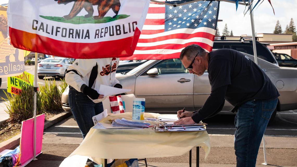 Jerry Cisco, of Rancho Cordova, gives his signature and personal information to Recall Gavin Newsom campaigners set up in the parking lot of Rivergate Shopping Center on Saturday, Jan. 23, 2021, in Rancho Cordova.
